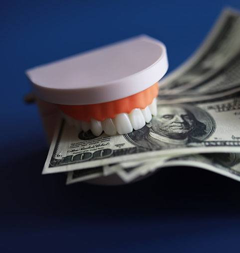 A fake jaw of teeth clasping dollar bills