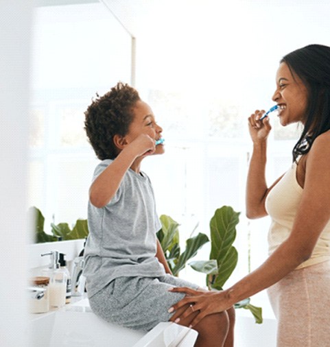 a parent brushing their teeth with their child