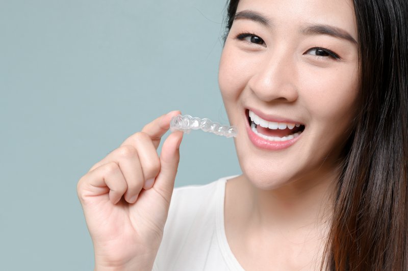 person smiling and holding Invisalign during cold and flu season