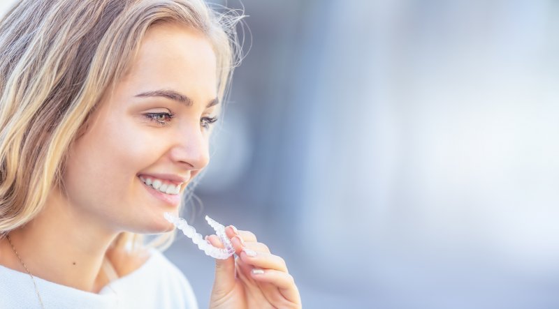 attractive woman smiling inserting clear Invisalign in Merrimack